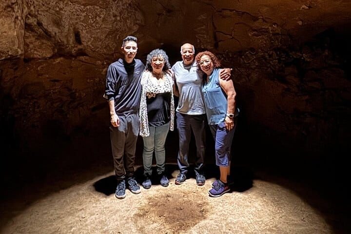 Una familia de cuatro posando bajo el haz de luz de la cueva
