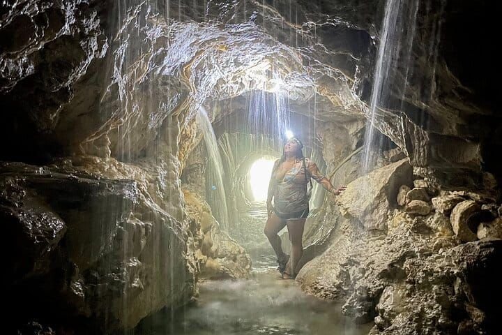 Walking the cave by headlamp through curtains of falling warm water