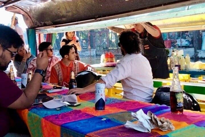 El grupo en la mesa mientras el mixólogo sirve detrás