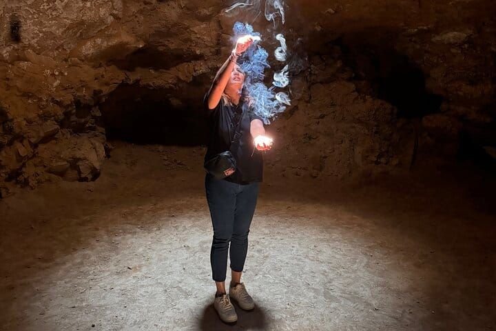 Juego de luces con bengalas dentro de la cueva, con el humo subiendo