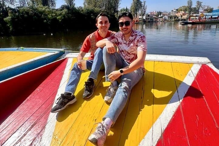 Dos pasajeros sentados al sol en la proa de la trajinera