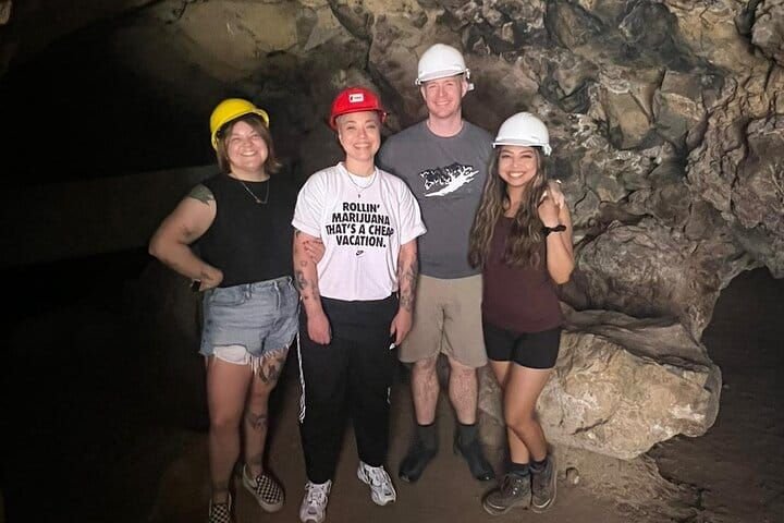 Cuatro visitantes con casco dentro de la cueva subterránea