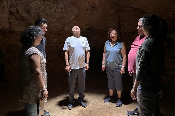 El grupo en círculo bajo la bóveda de la cueva, escuchando al guía