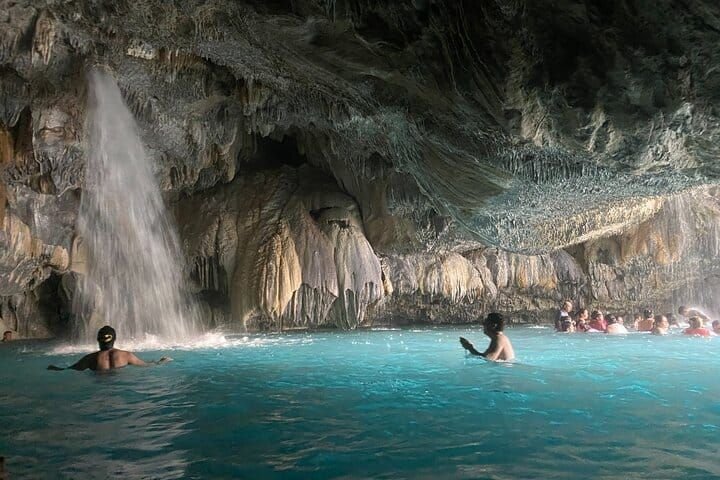 An interior waterfall falling into the cave's turquoise pool